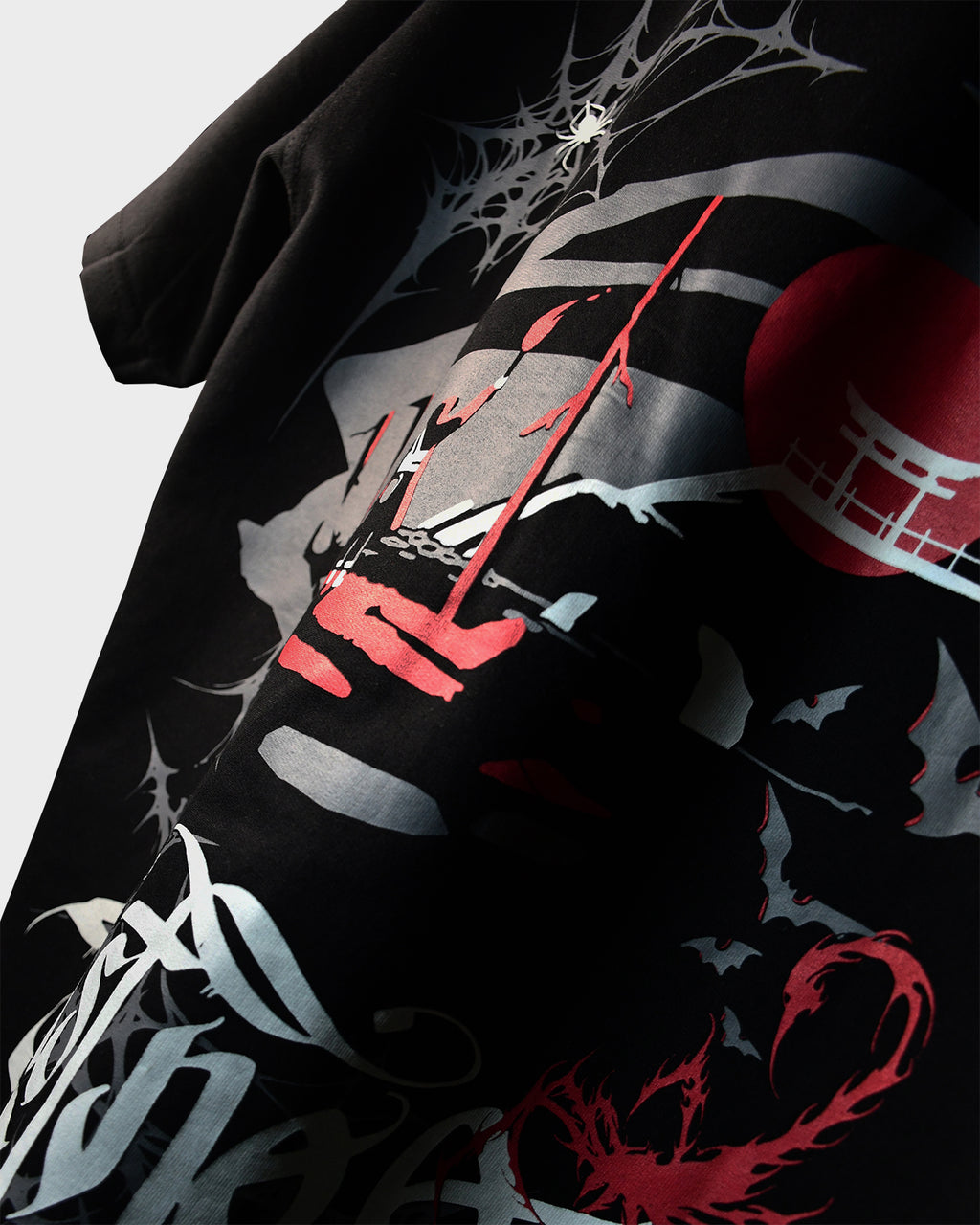 Close-up of TWYN Akai Samurai t-shirt featuring red sun, samurai scene, bats, and white web artwork on black french terry cotton fabric
