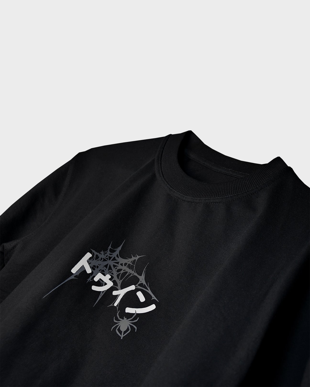 Close-up of TWYN Akai Samurai black t-shirt featuring white Japanese text and spider web graphic on a light background