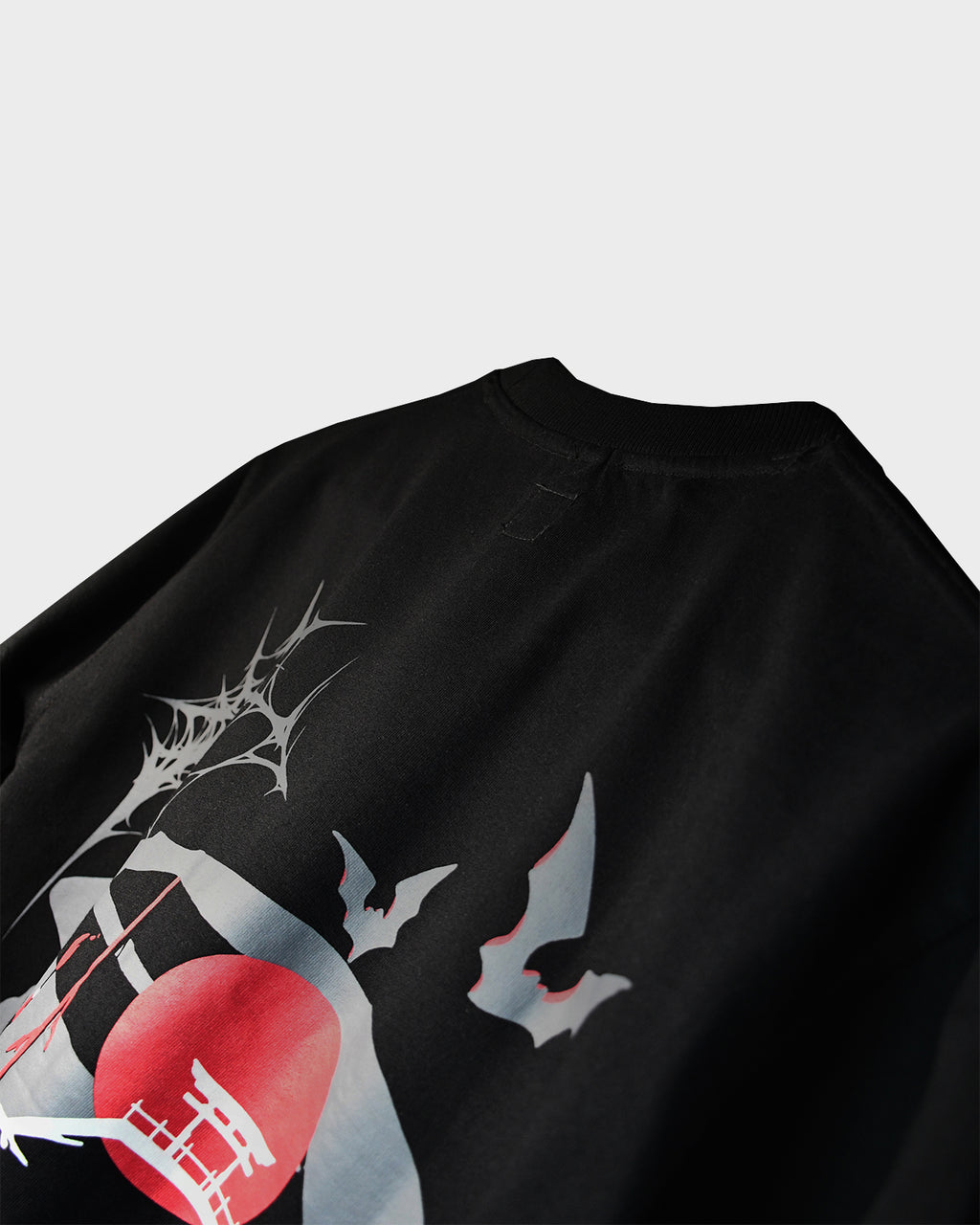 Close-up of TWYN Akai Samurai black t-shirt featuring red sun, bats, and samurai-themed back graphic on a light background