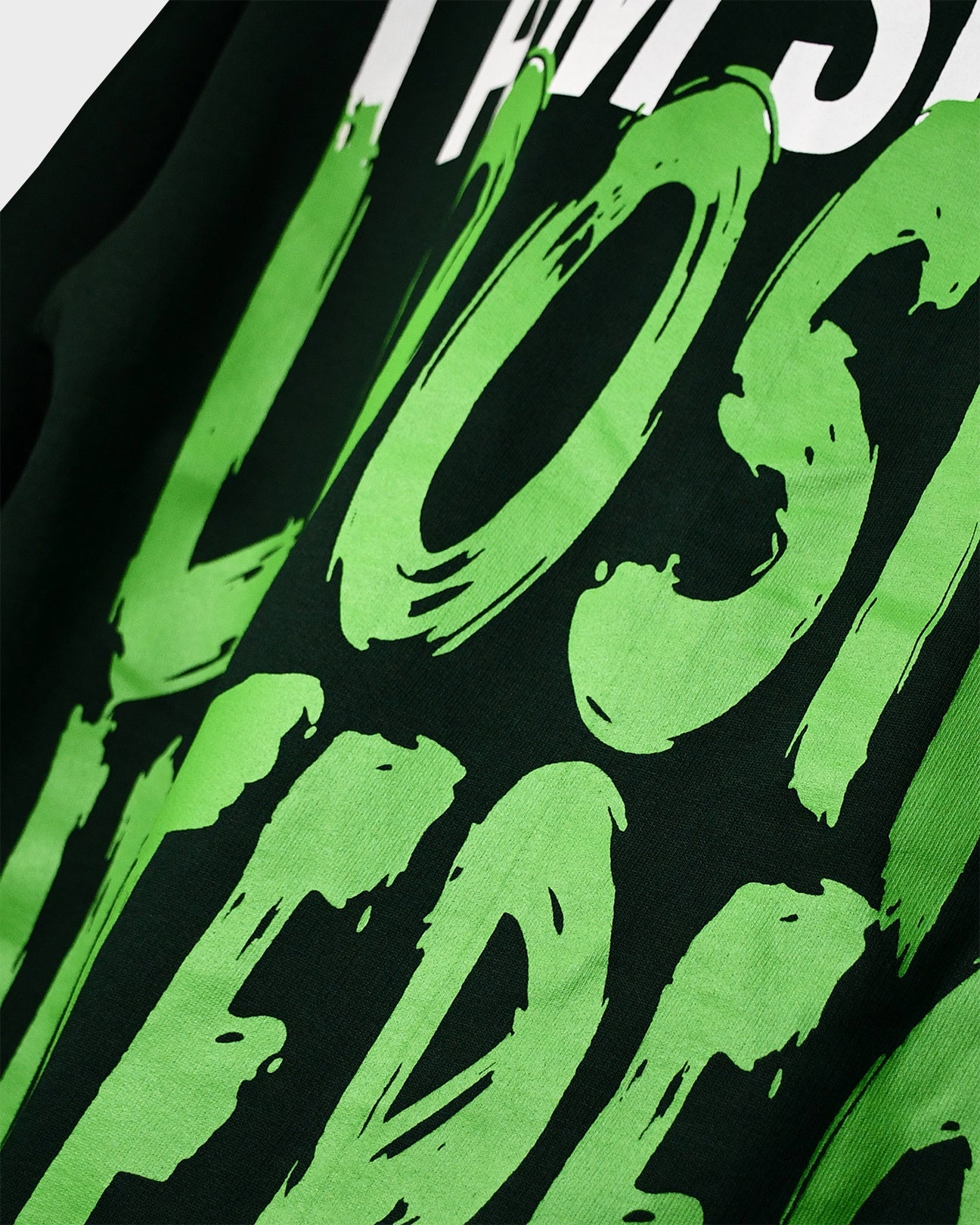 Close-up of TWYN Midori Ascend green oversized t-shirt with bold neon green back print reading ‘I am slowly losing interest on everything