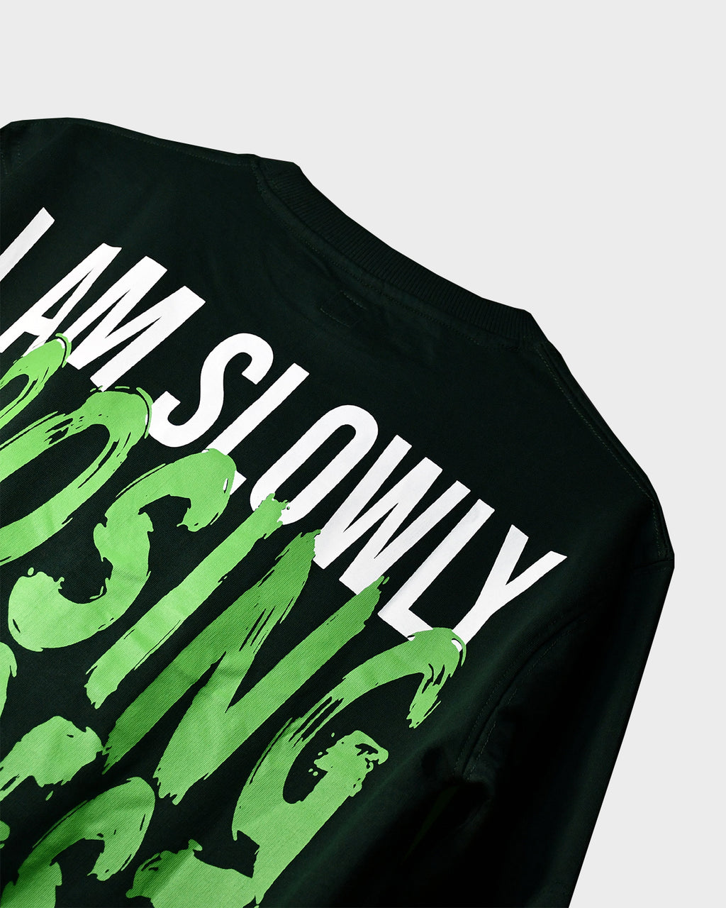 Close-up of TWYN Midori Ascend green oversized t-shirt with bold neon green back print reading ‘I am slowly losing interest on everything