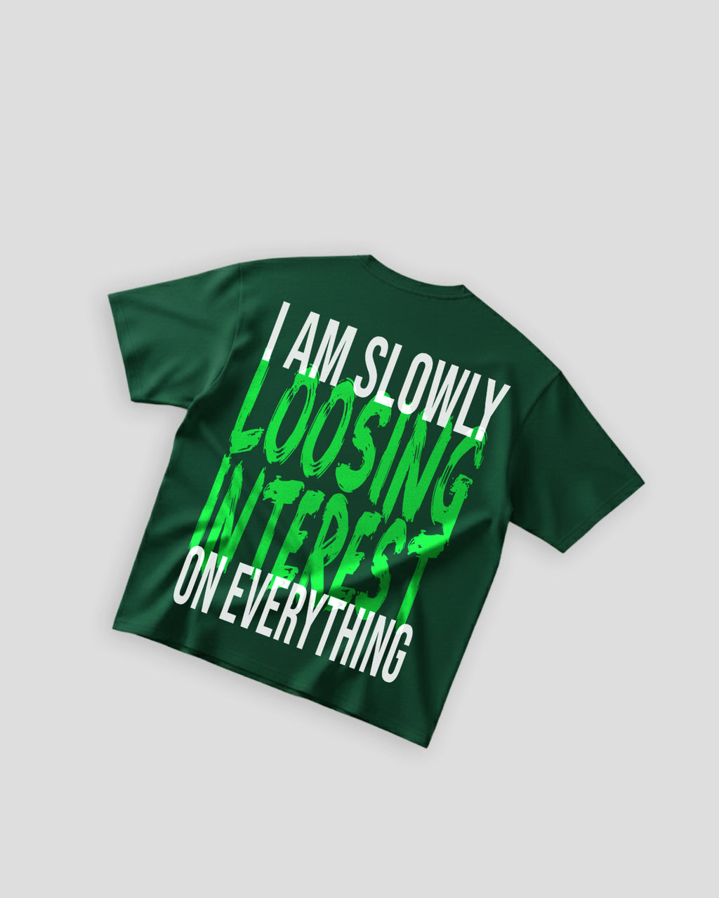 Flat lay of TWYN Midori Ascend green oversized t-shirt with bold neon green back print reading ‘I am slowly losing interest on everything