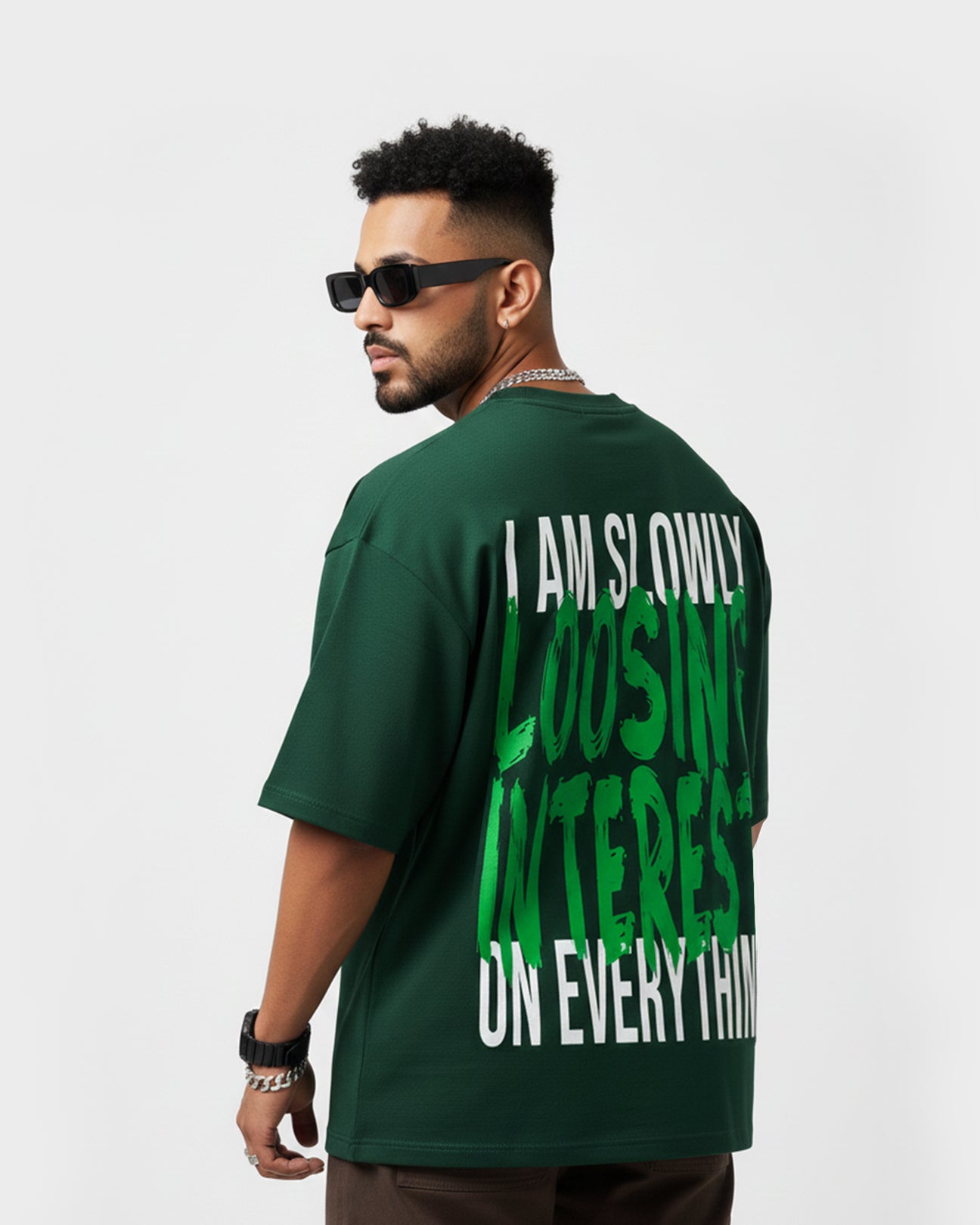 Back view of model wearing TWYN Midori Ascend green oversized t-shirt with bold neon green ‘I am slowly losing interest on everything’ graphic text