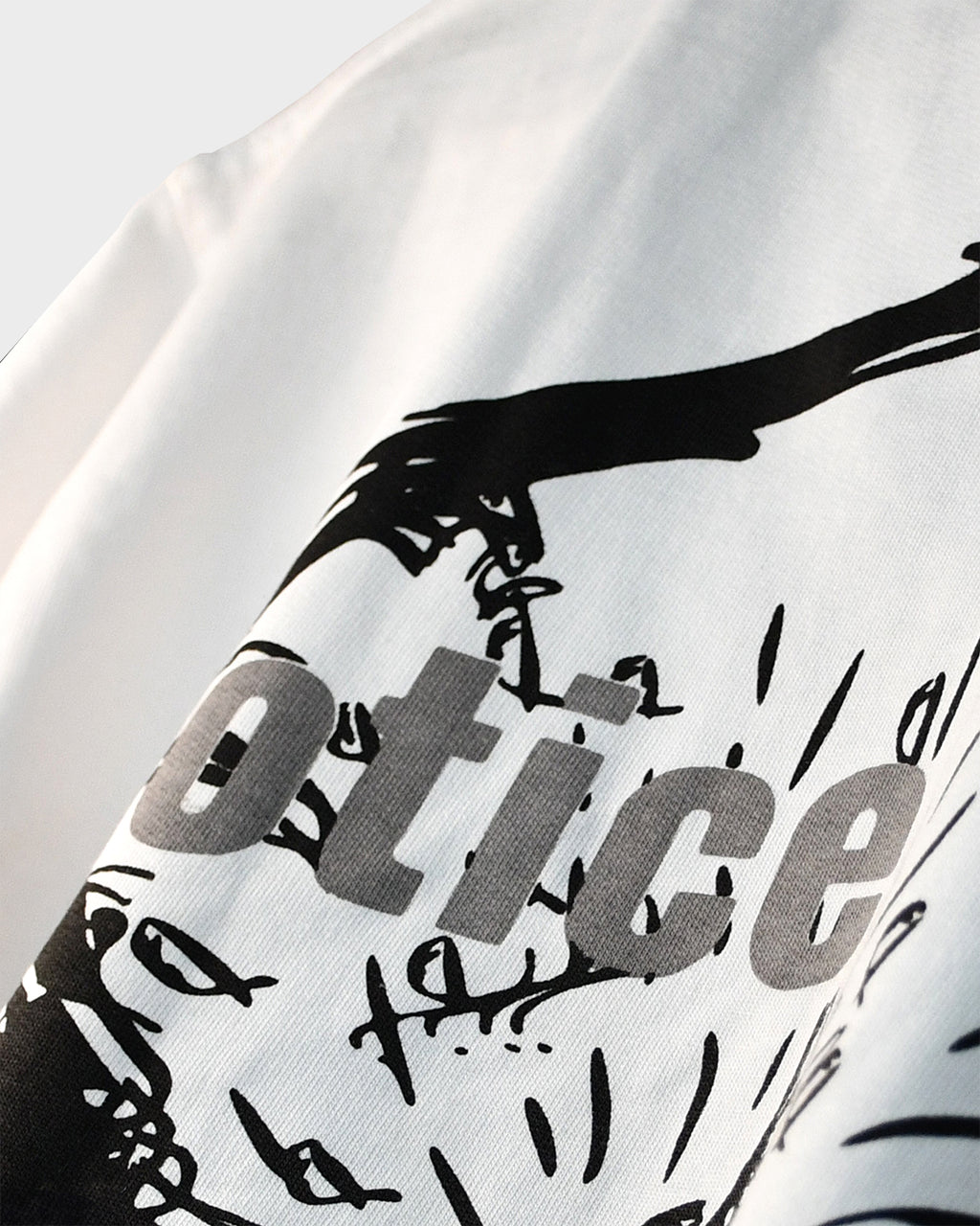 Close-up of black ‘Notice’ graphic print on TWYN white oversized t-shirt