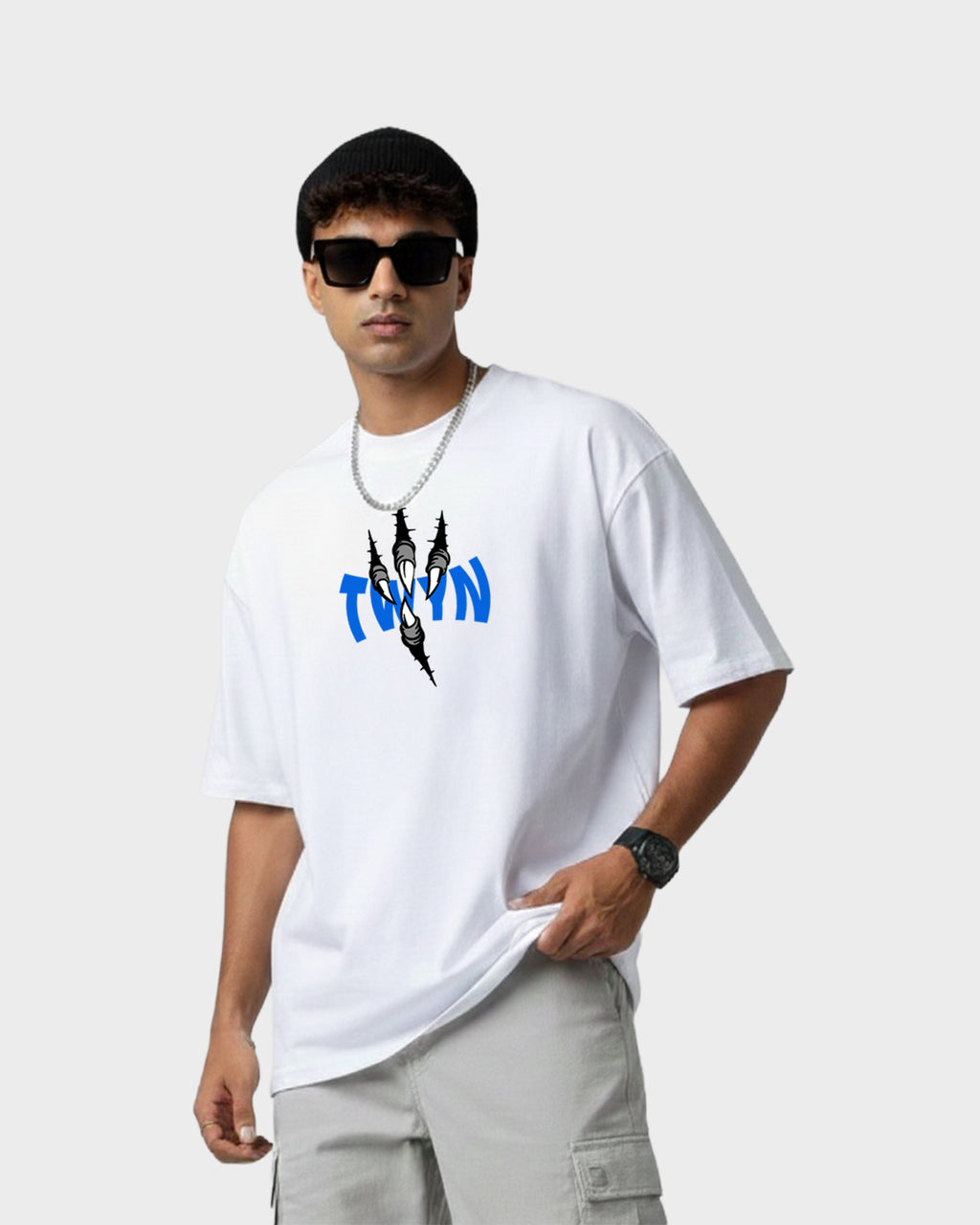 Model wearing TWYN white oversized t-shirt with blue TWYN logo and black claw-mark graphic on the chest